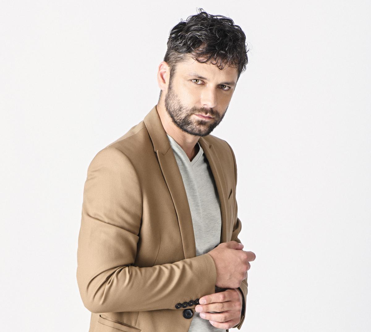 Actorul Alecsandru Dunaev, într-un costum bej, fotografie de studio pe fundal alb