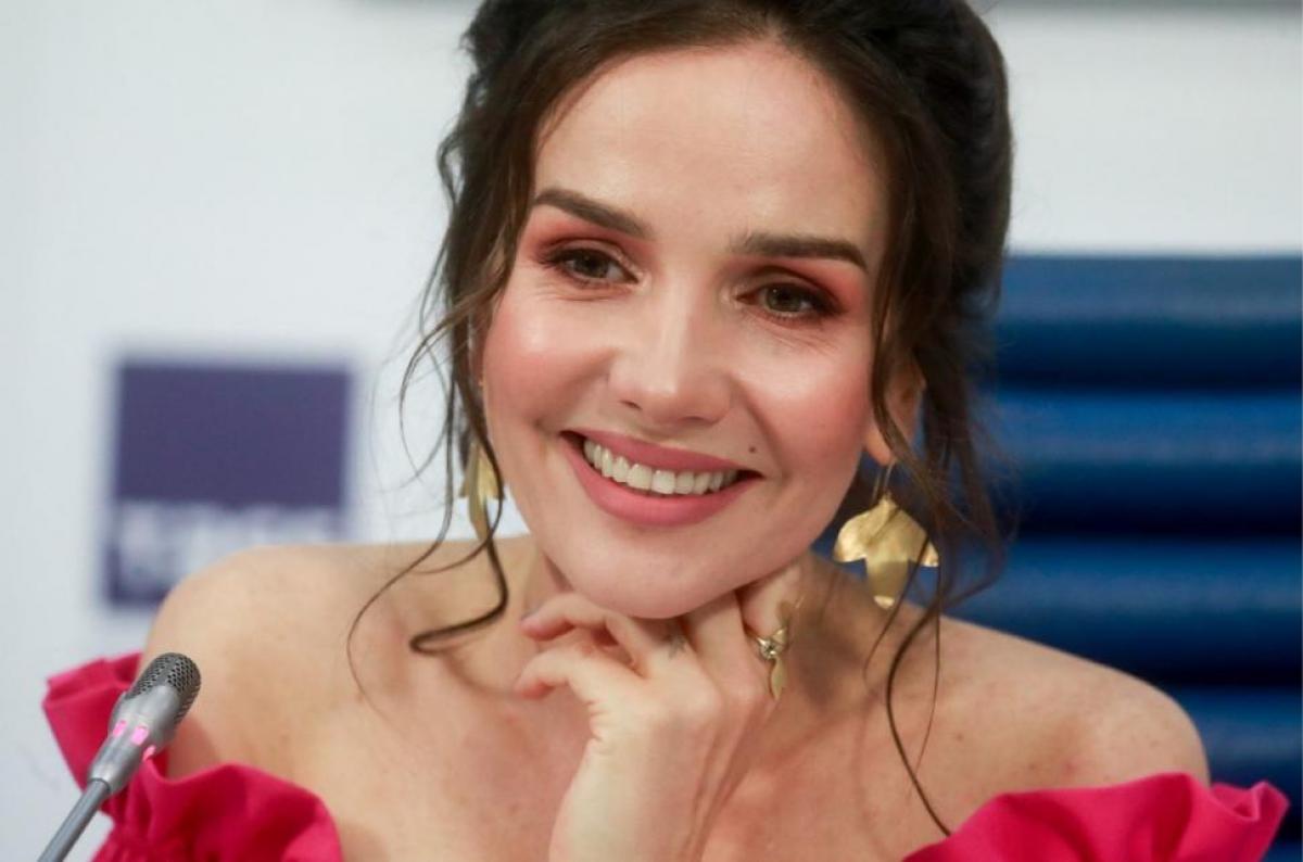 Natalia Oreiro, într-o rochie roșie cu umerii goi și cercei aurii supradimensionați.