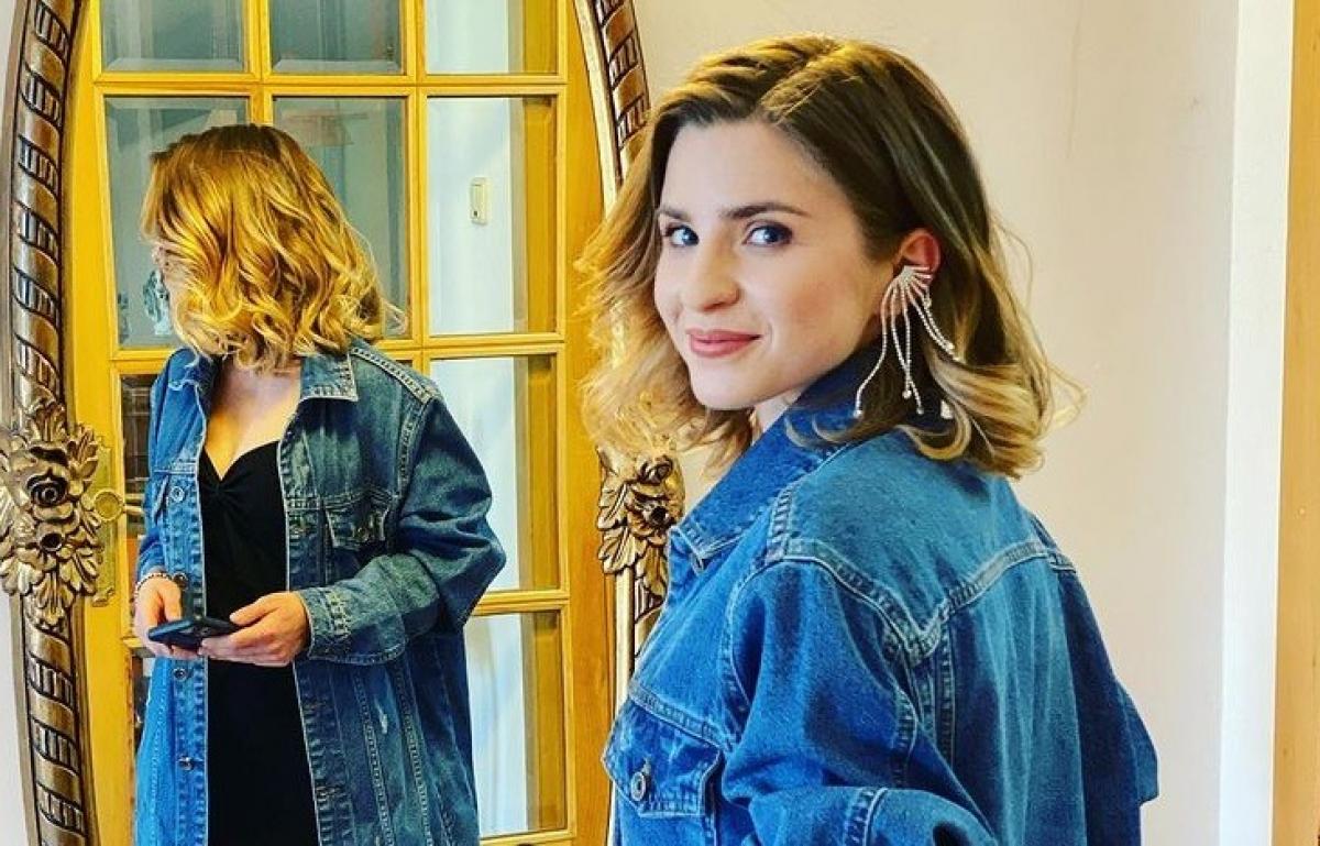 Cristina Ciobănașu, îmbrăcată cu o jacheta din jeans, stă în fața unei oglinzi.
