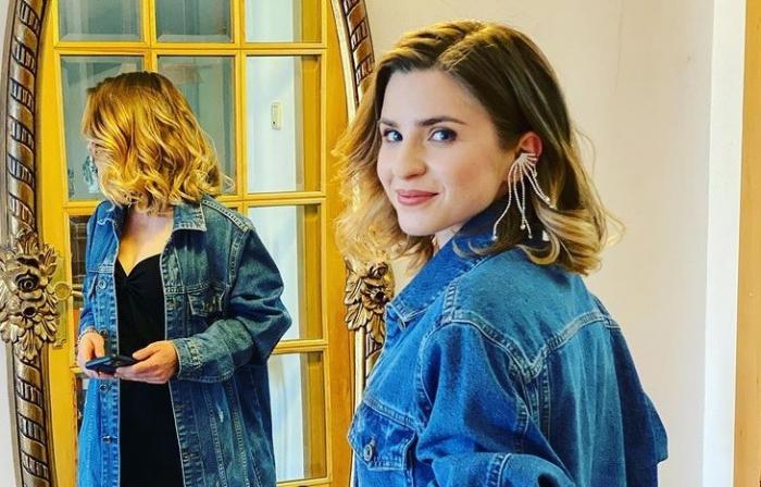 Cristina Ciobănașu, îmbrăcată cu o jacheta din jeans, stă în fața unei oglinzi.