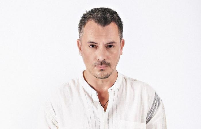 Răzvan Fodor, îmbrăcat într-o bluză albă, privește drept în obiectivul camerei de fotografiat.