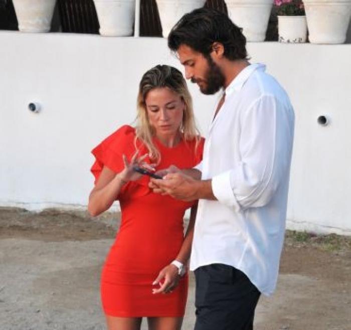 Diletta Leotta poartă o rochie roșie scurtă și Can Yaman poartă o cămașă albă cu pantaloni de culoare închisă
