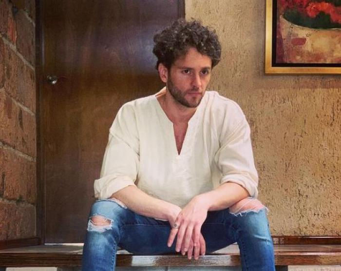 Christopher Uckermann poartă blugi rupți în genunchi și o bluză albă