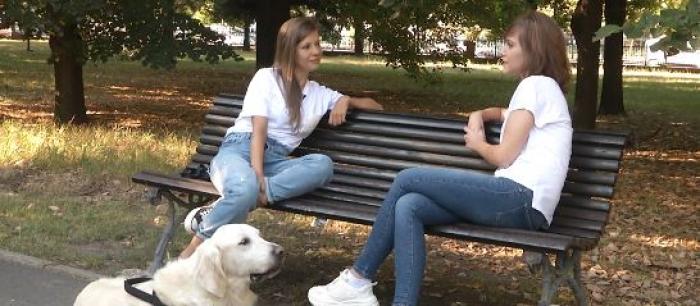 Carla Alina Buleanu și Alexandra Gherman stau pe bancă în parc alături de cățelușa Happy