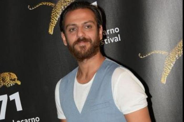 Erkan Kolçak Köstendil poartă un tricou alb și o vestă albastră