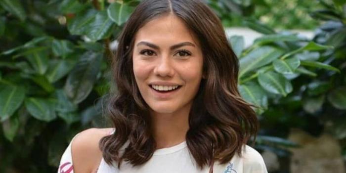 Demet Ozdemir poartă o bluză albă și are părul ondulat, desprins
