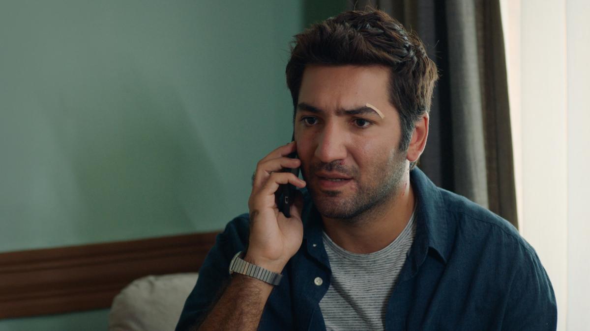 Berkay Ateş poartă un tricou gri și o cămașă albastru închis