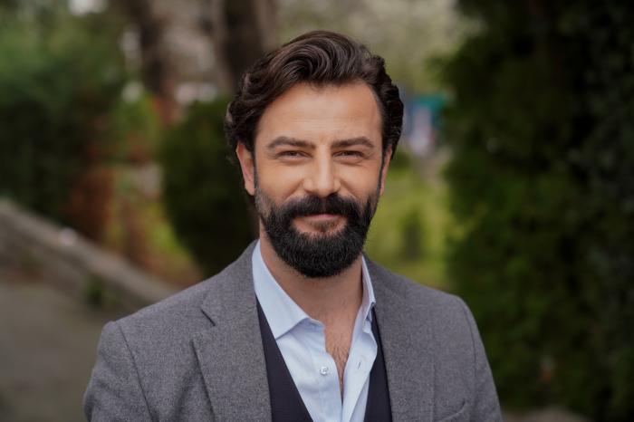 Gökberk Demirci poartă o cămașă albastră și un sacou gri