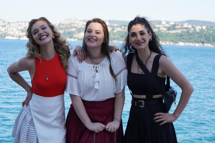 Melisa Döngel poartă o fustă albă și o bluză roșie fără mâneci