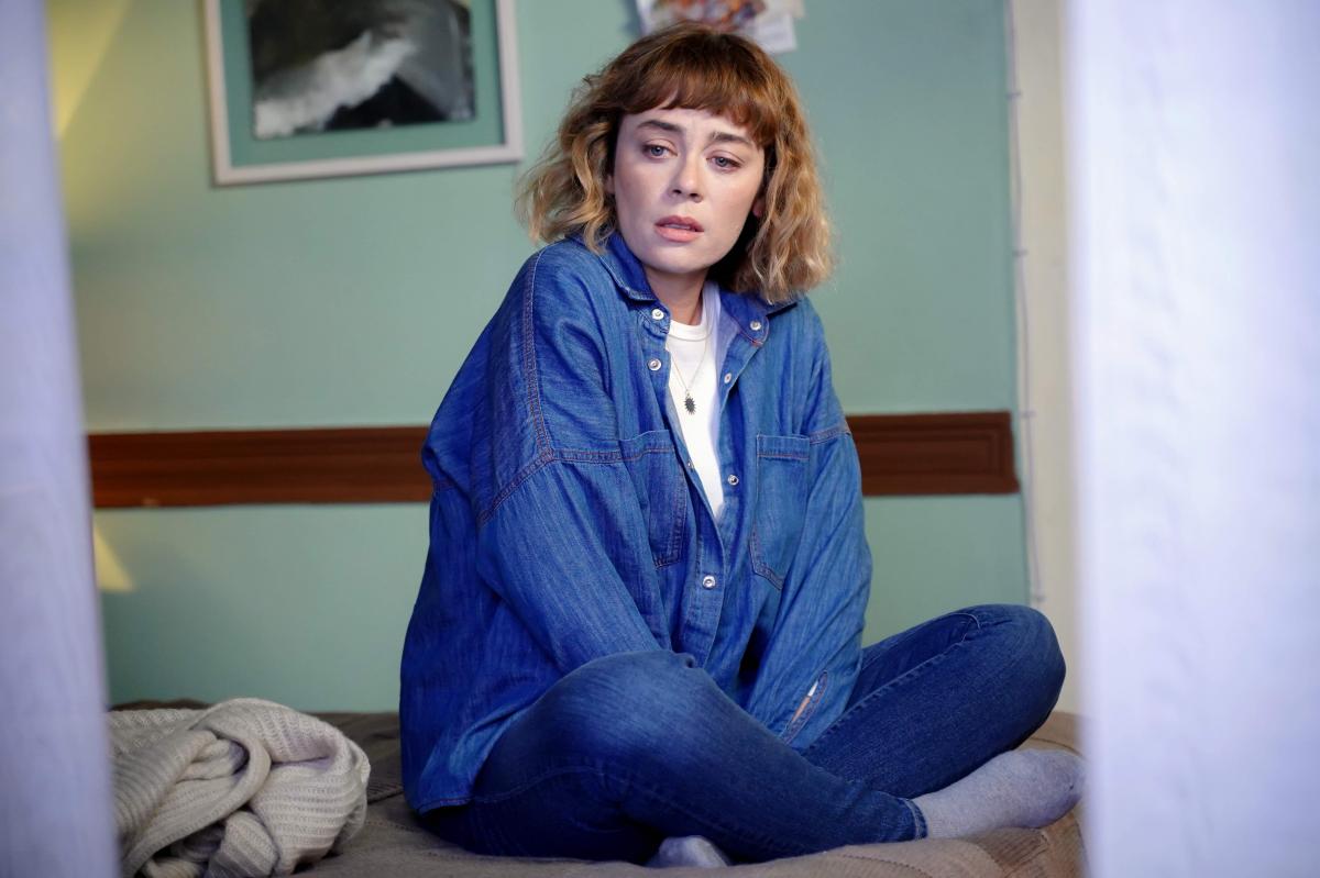 Demet Evgar poartă un tricou alb și bluză albastră cu mâneci lungi