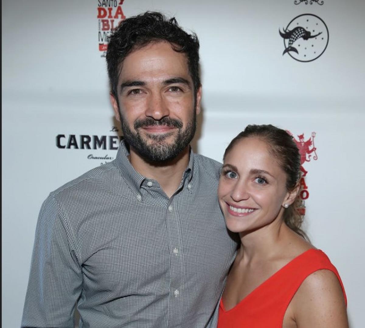 Alfonso Herrera poartă o cămașă gri și stă alături de mama copiilor săi