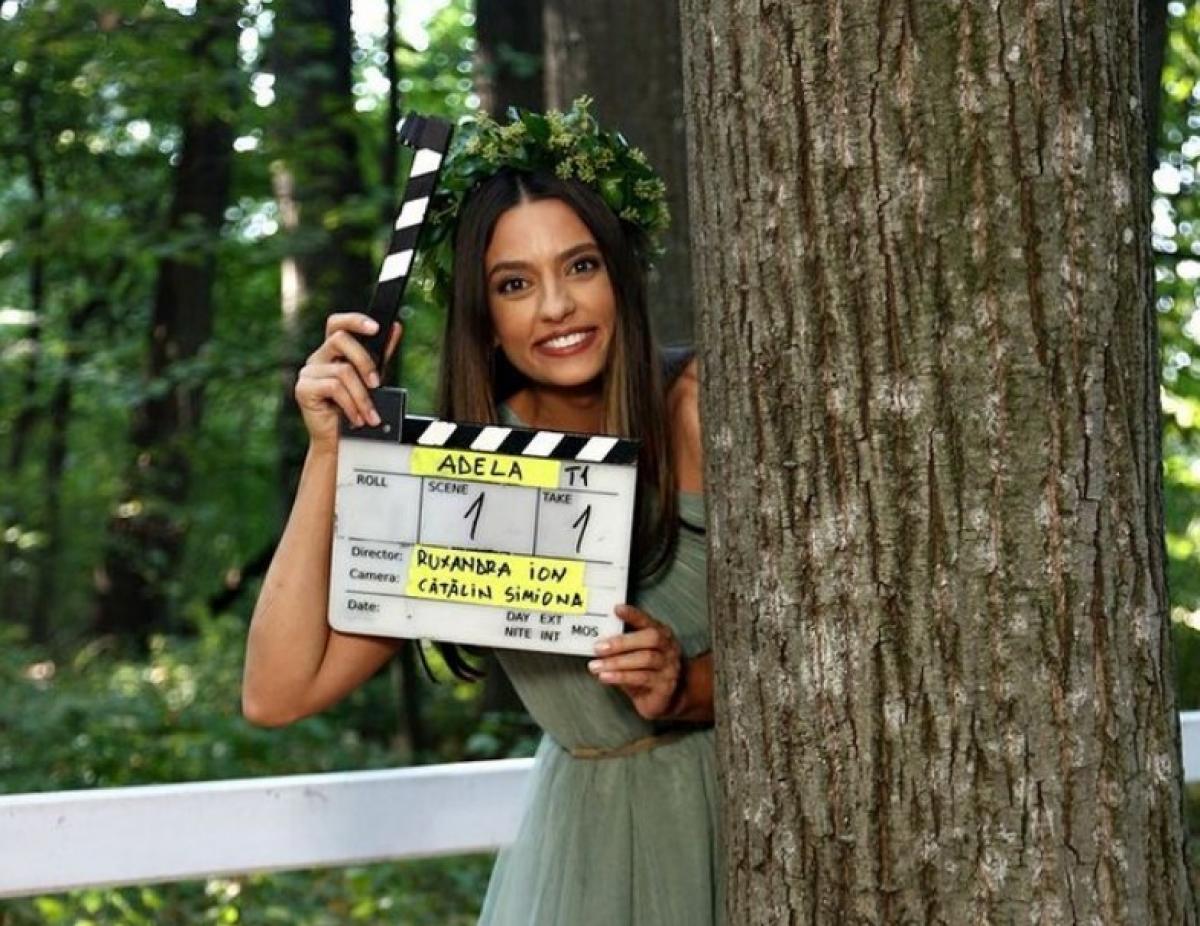 Oana Moșneagu poartă o rochie verde și are o coroniță pe cap