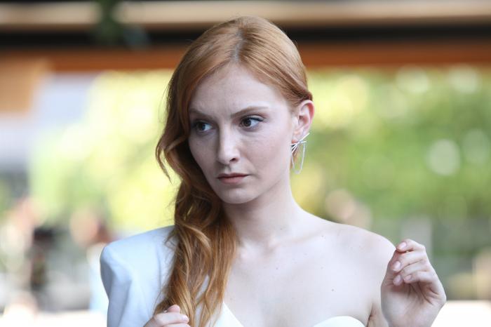 Başak Gümülcinelioğlu poartă o rochie albă și are părul desprins