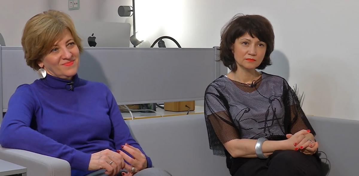 Oana Gheorghiu este îmbrăcată într-o bluză albastră și stă lângă prietena sa, Carmen Uscatu