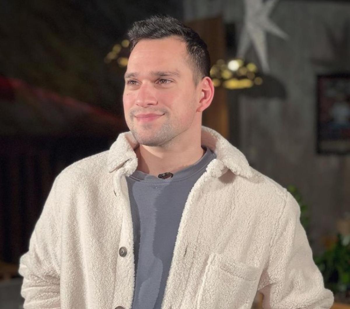 Vlad Gherman poartă un tricou gri și o jachetă albă