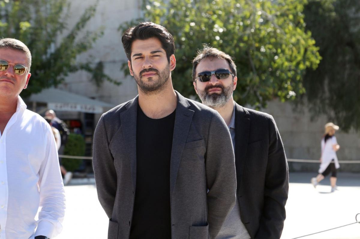 Burak Özçivit poartă un tricou negru și un sacou închis la culoare