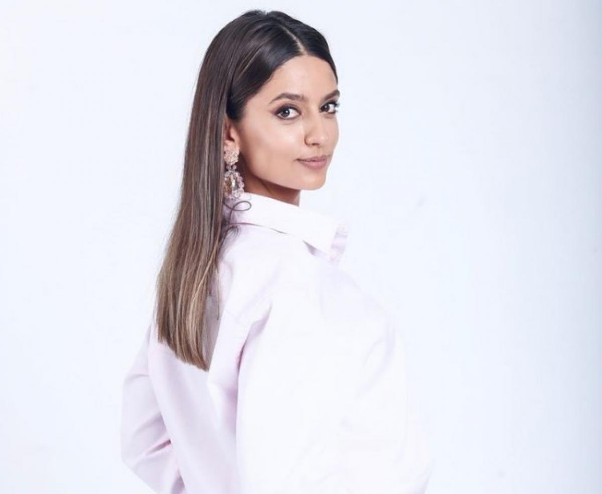 Oana Mosneagu poartă o cămașă albă și are părul desprins