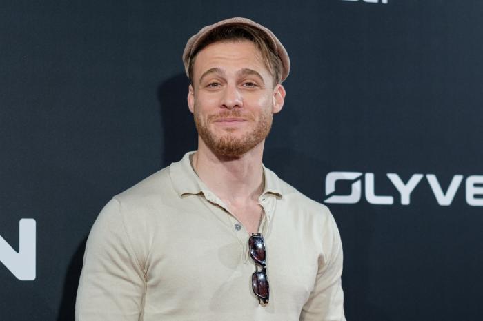 Kerem Bürsin poartă un tricou deschis la culoare și ochelari de soare