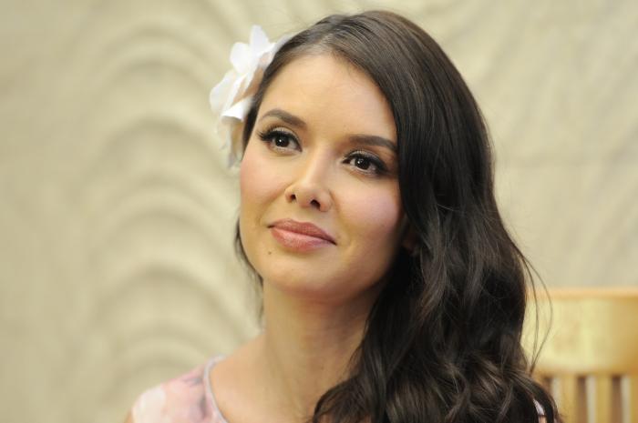 Marlene Favela poartă părul lung, desprins și are o floare albă în păr