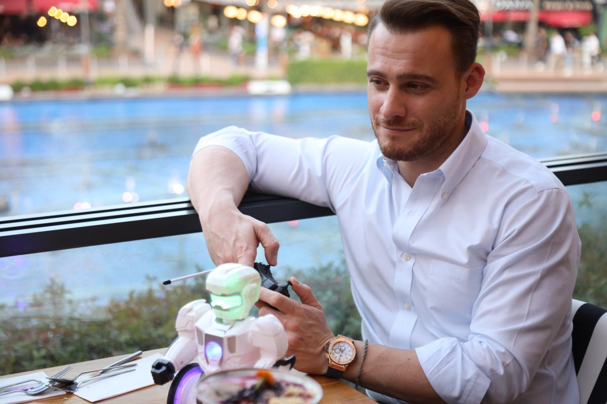 Kerem Bursin poartă o cămașă și stă la un restaurant