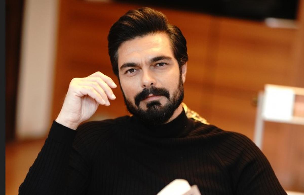 Halil Ibrahim Ceyhan poartă o maletă neagră și ține o carte în mână