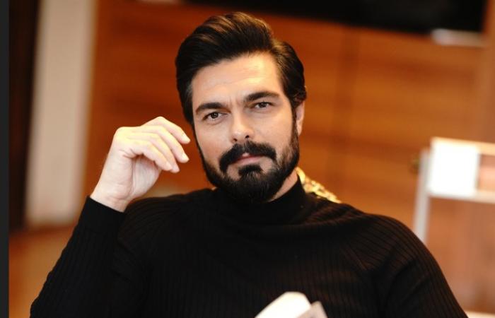 Halil Ibrahim Ceyhan poartă o maletă neagră și ține o carte în mână