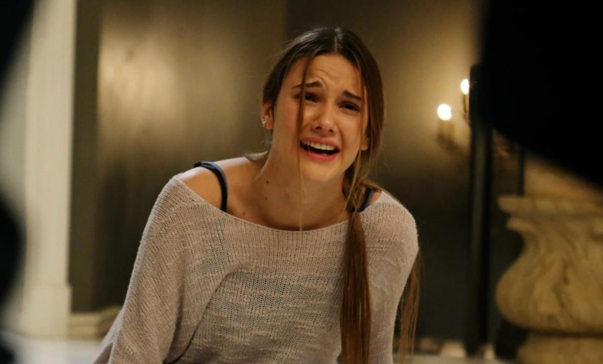 Alina Boz poartă o bluză cu mâneci lungi și are o coadă prinsă într-o parte