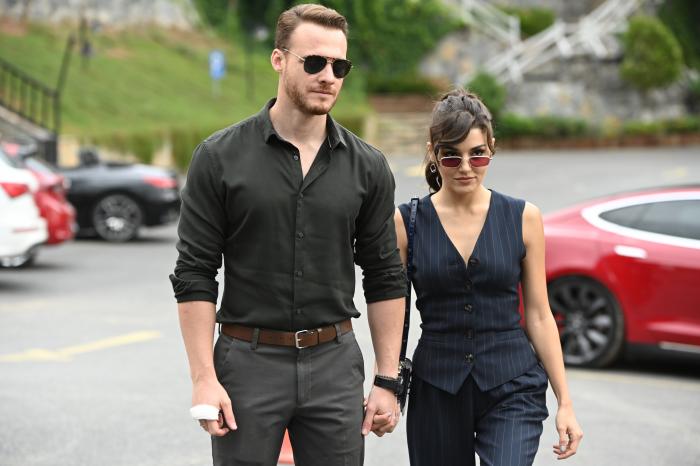 Hande Ercel și Kerem Bursin se țin de mână, sunt îmbrăcați în negru și poartă ochelari de vedere