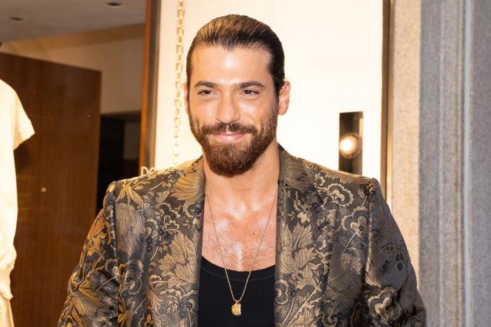 Can Yaman poartă un tricou negru și un sacou cu imprimeu floral închis la culoare