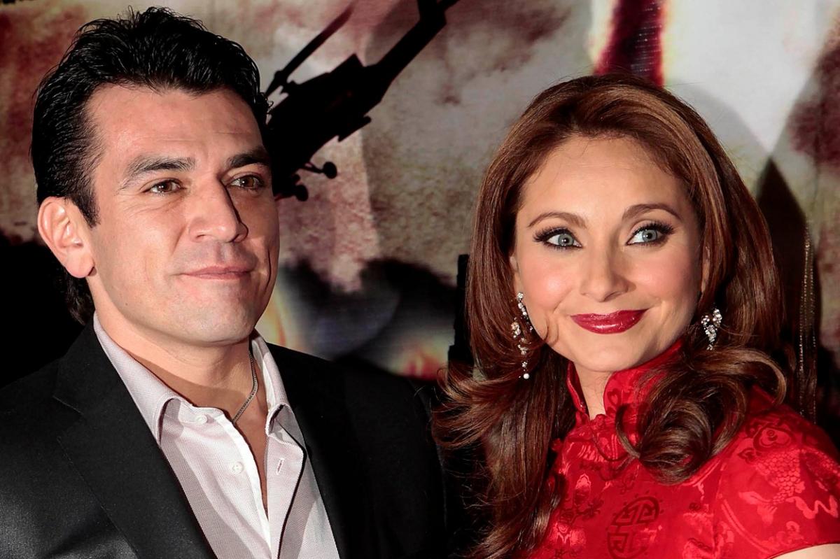 Jorge Salinas poartă o cămașă albă și un costum negru, iar Elizabeth Alvarez poartă o rochie roșie și zâmbește