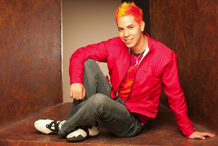 Christian Chavez poartă blugi și o cămașă roșie