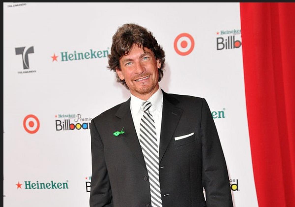 Sebastián Ligarde poartă costum, zâmbește și are părul lung și ondulat