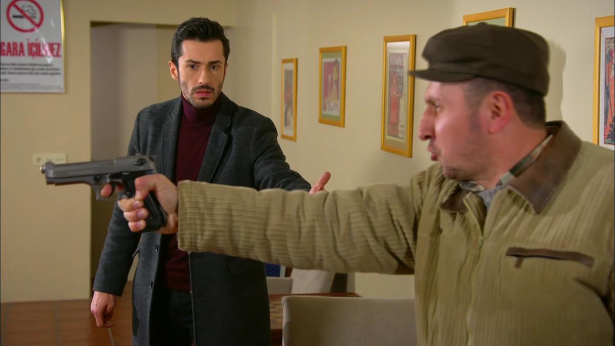 Emrah Akduman poartă un pulover negru și un sacou albastru