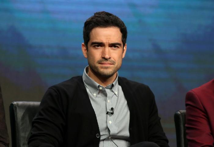 Alfonso Herrera poartă o cămașă deschisă la culoare și un pulover negru