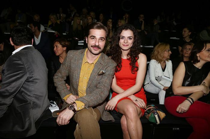 Özge Özpirinçci poartă o rochie roșie scurtă și își ține mâinile pe picioare