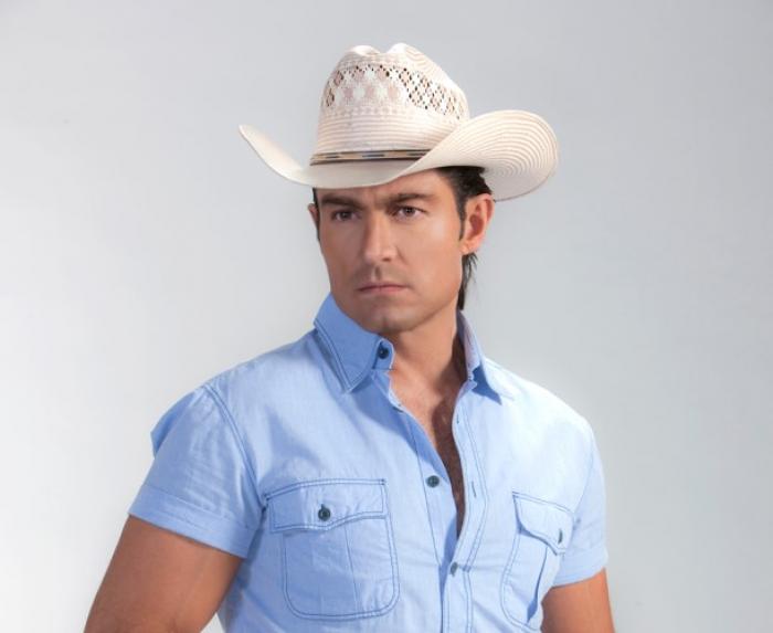 Fernando Colunga poartă o cămașă albastră cu mâneci scurte și are o pălărie