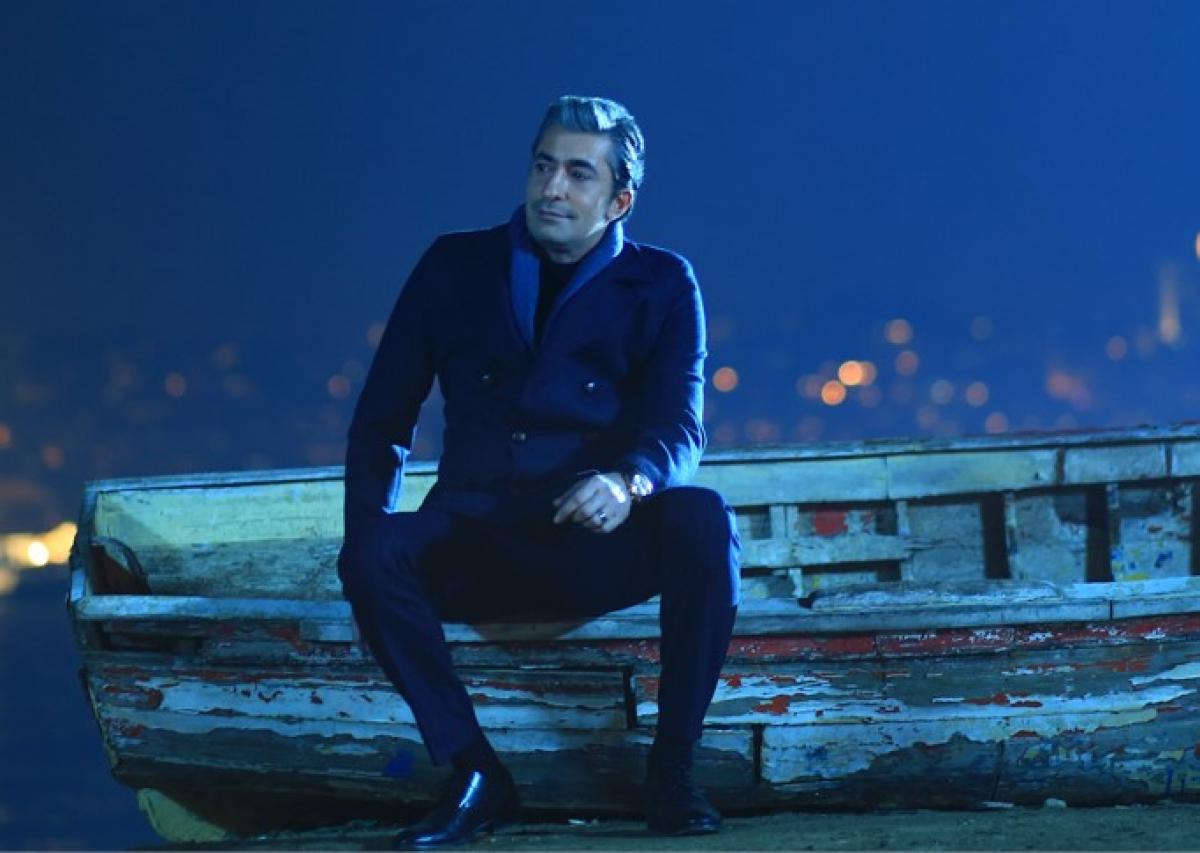 Erakan Petekkaya poartă o ținută all-black și stă cu mâna stângă pe picior
