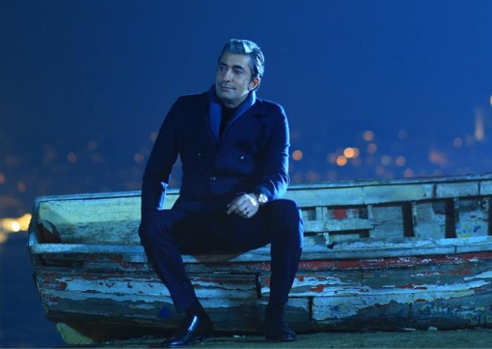 Erakan Petekkaya poartă o ținută all-black și stă cu mâna stângă pe picior