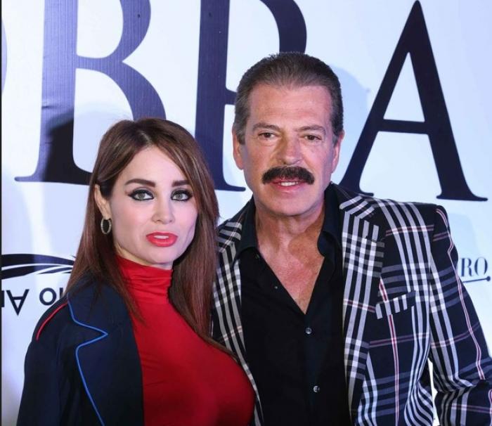 Sergio Goyri poartă o cămașă neagră și stă alături de partenera sa