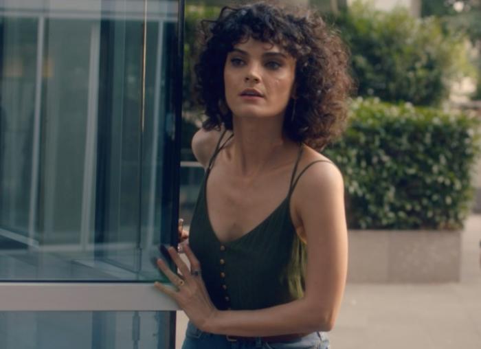 Nazlı Senem Ünal poartă un maiou negru, are părul scurt și ondulat și stă în spatele unei clădiri