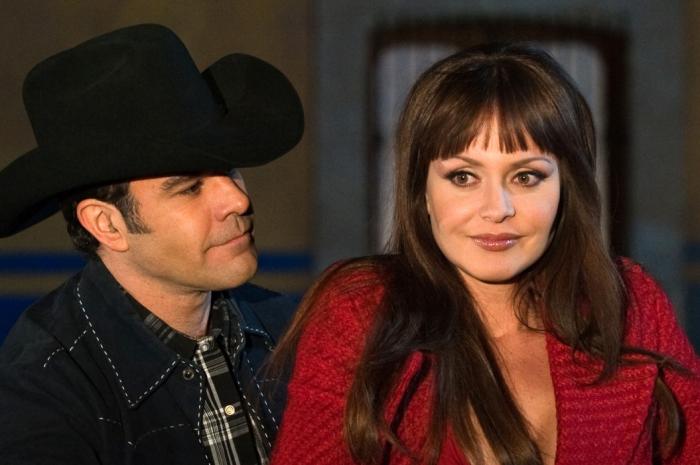 Gabriela Spanic poartă o rochie vișinie, are părul lung, închis la culoare și cu breton și stă lângă Eduardo Capetillo