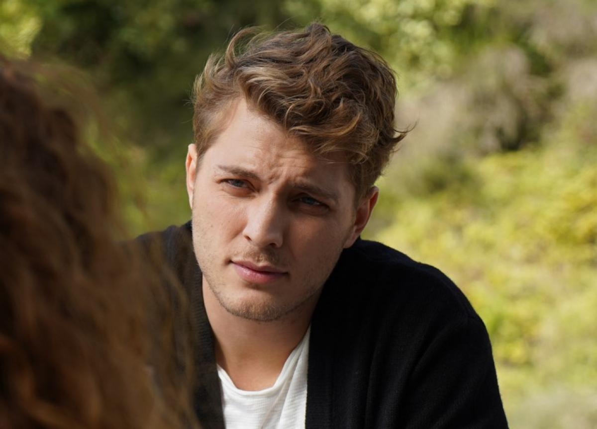 Burak Tozkoparan poartă un tricou alb și o cămașă neagră