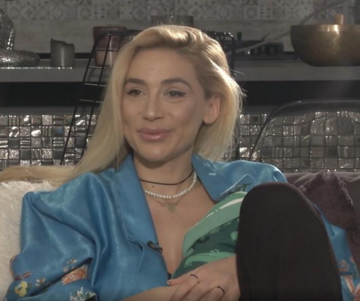 Andreea Ioniță poartă părul desprins, își ține bebelușul în brațe și zâmbește