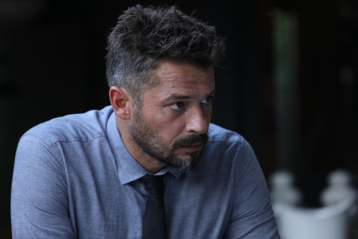 Anıl İlter este îmbrăcat într-o cămașă albastră și poartă cravată