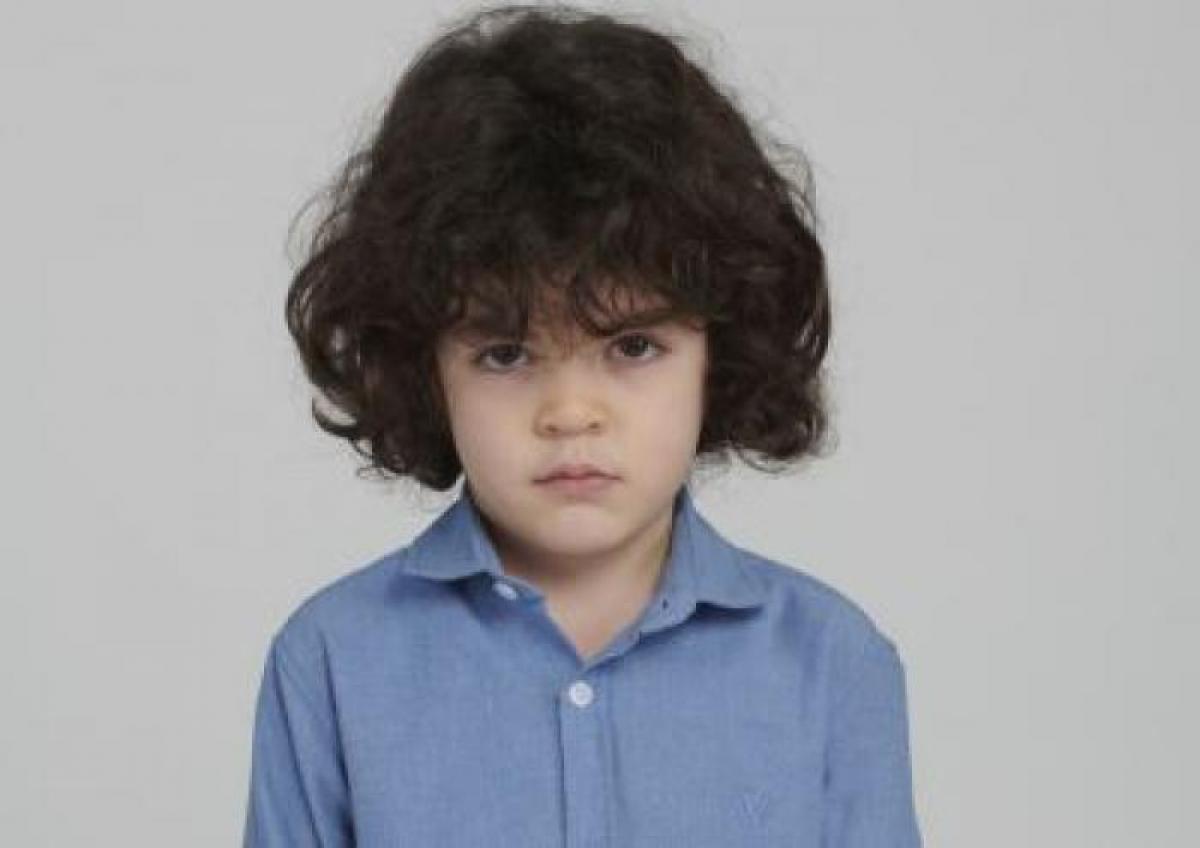 Berat Rüzgâr Özkan poartă o cămașă albastră și are părul cârlionțat.