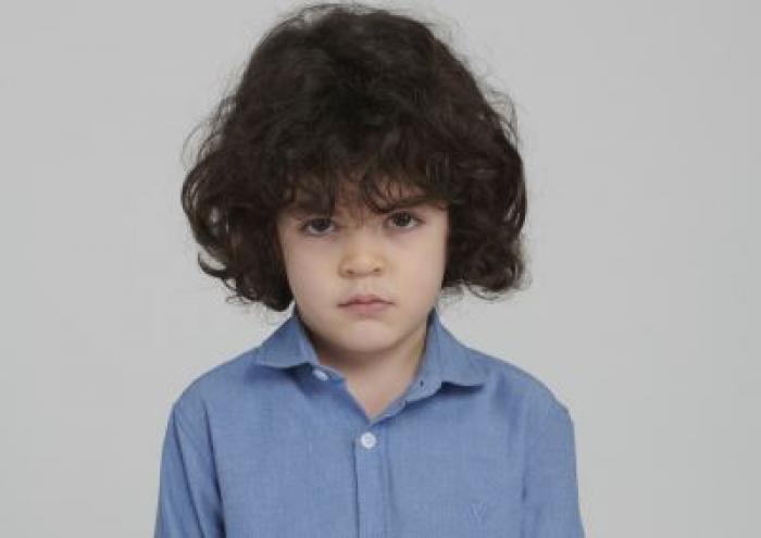 Berat Rüzgâr Özkan poartă o cămașă albastră și are părul cârlionțat.