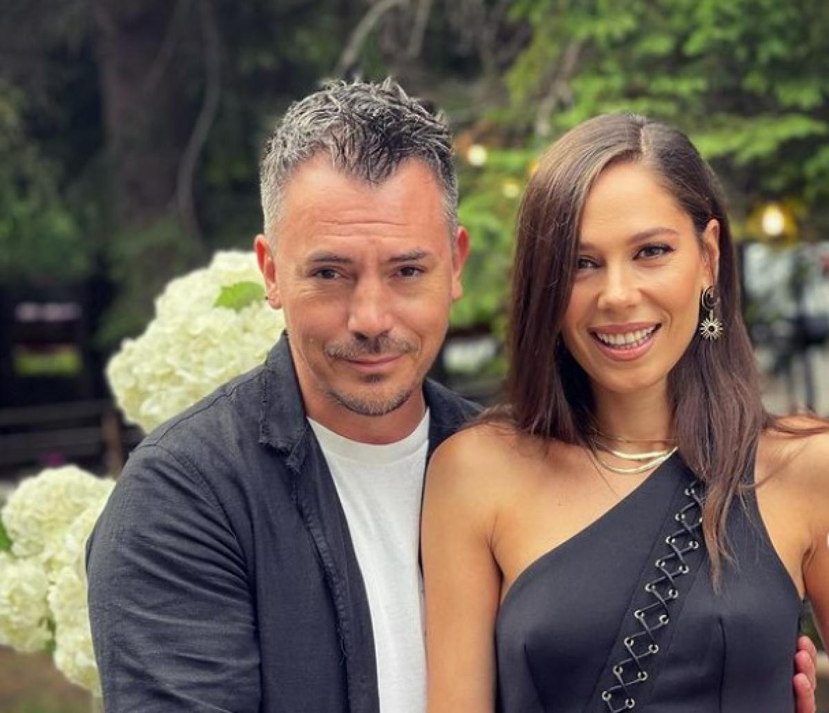 Răzvan Fodor poartă un tricou alb și un sacou negru și stă în spatele Irinei Fodor. Aceasta poartă o rochie fără mâneci și are părul desprins