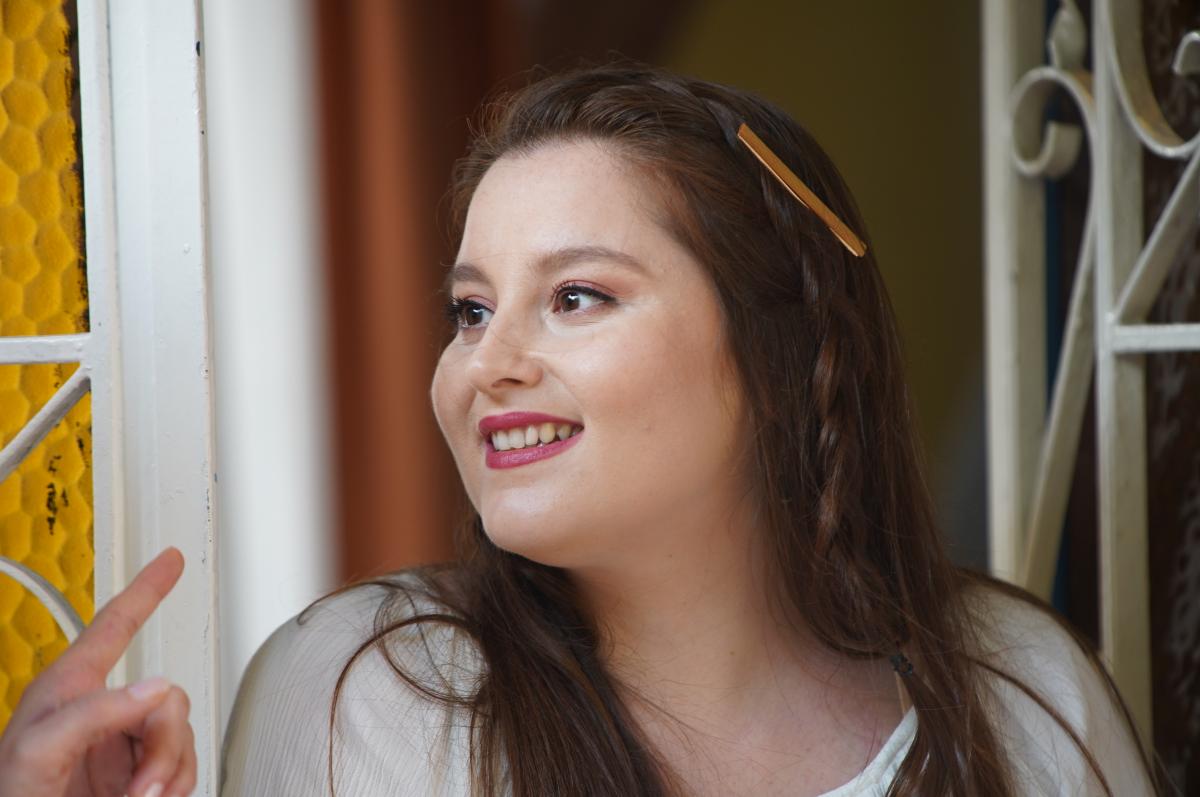 Elçin Afacan zâmbește și se uită în depărtare. Actrița poartă părul desprins și un machiaj simplu