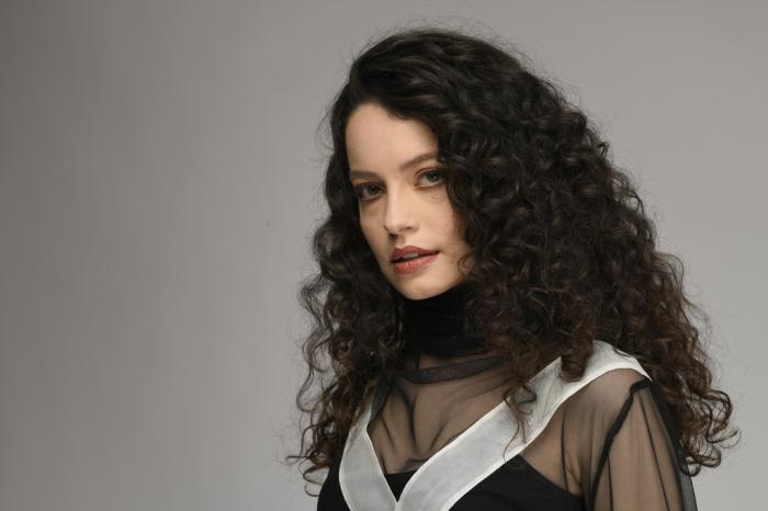 Gizem Arıkan poartă o bluză elegantă, are părul desprins și un machiaj de seară