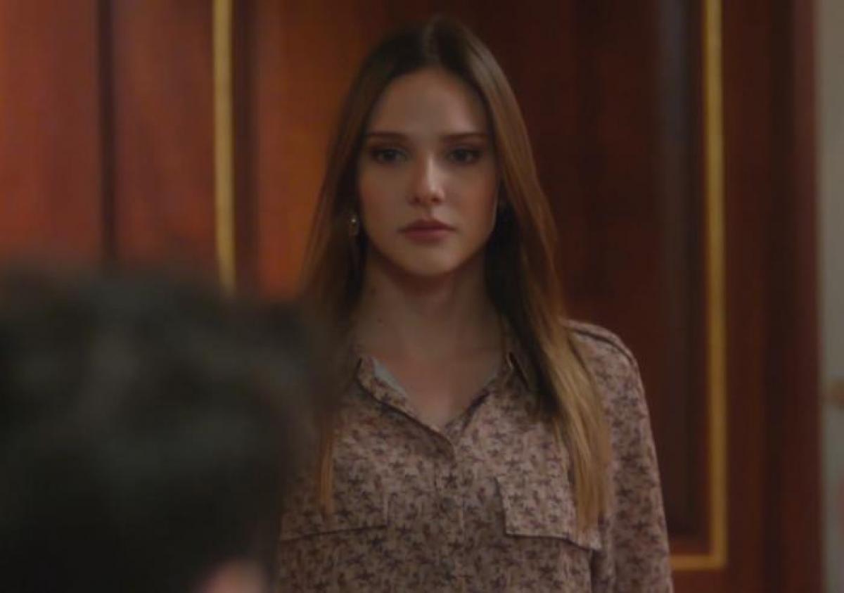 Alina Boz poartă o bluză cu mâneci lungi cu flori și are părul desprins